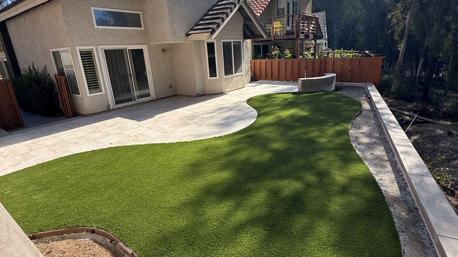 Finished backyard with a curved concrete patio and artificial turf, Carlsbad
